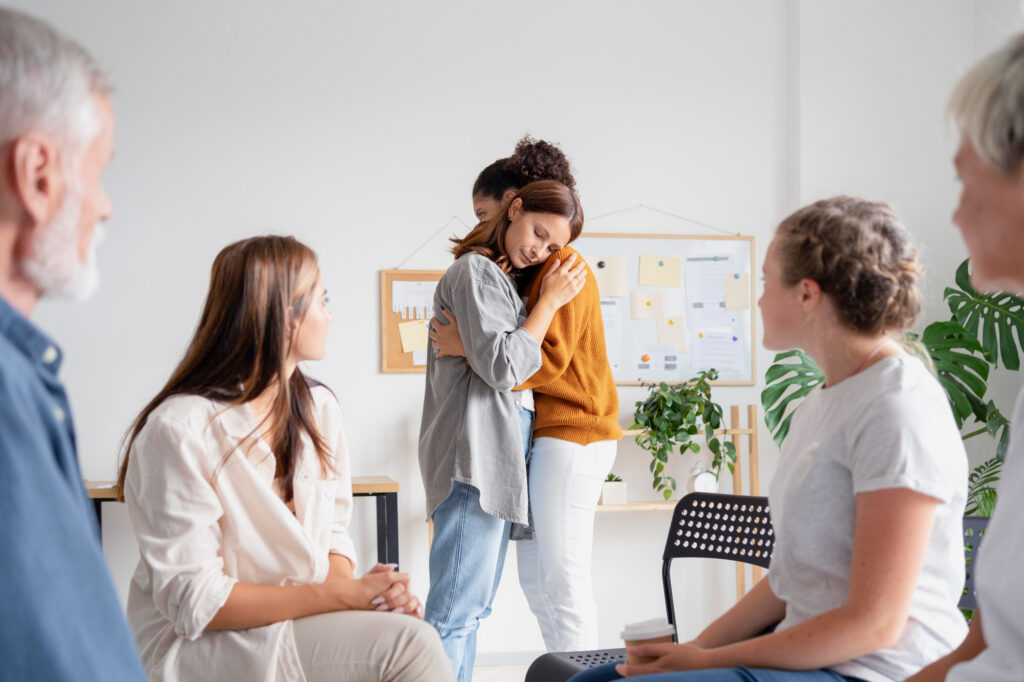 Two women embracing during a group therapy session for addiction treatment at Axis Behavioral Health.