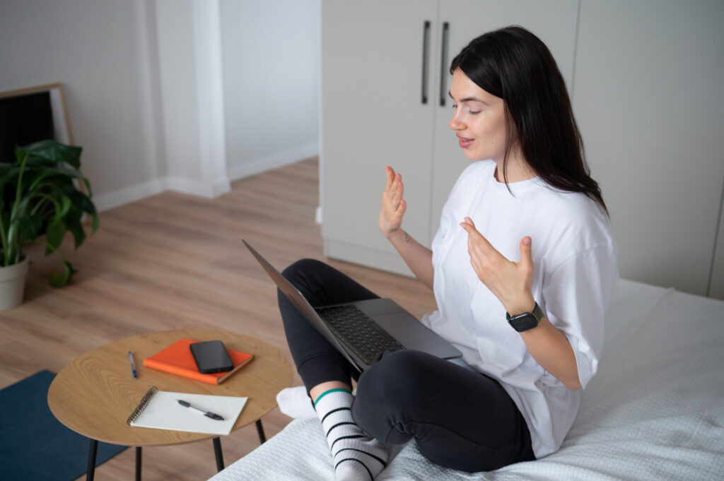 Woman participating in virtual addiction treatment from her bed using a laptop in Wisconsin.