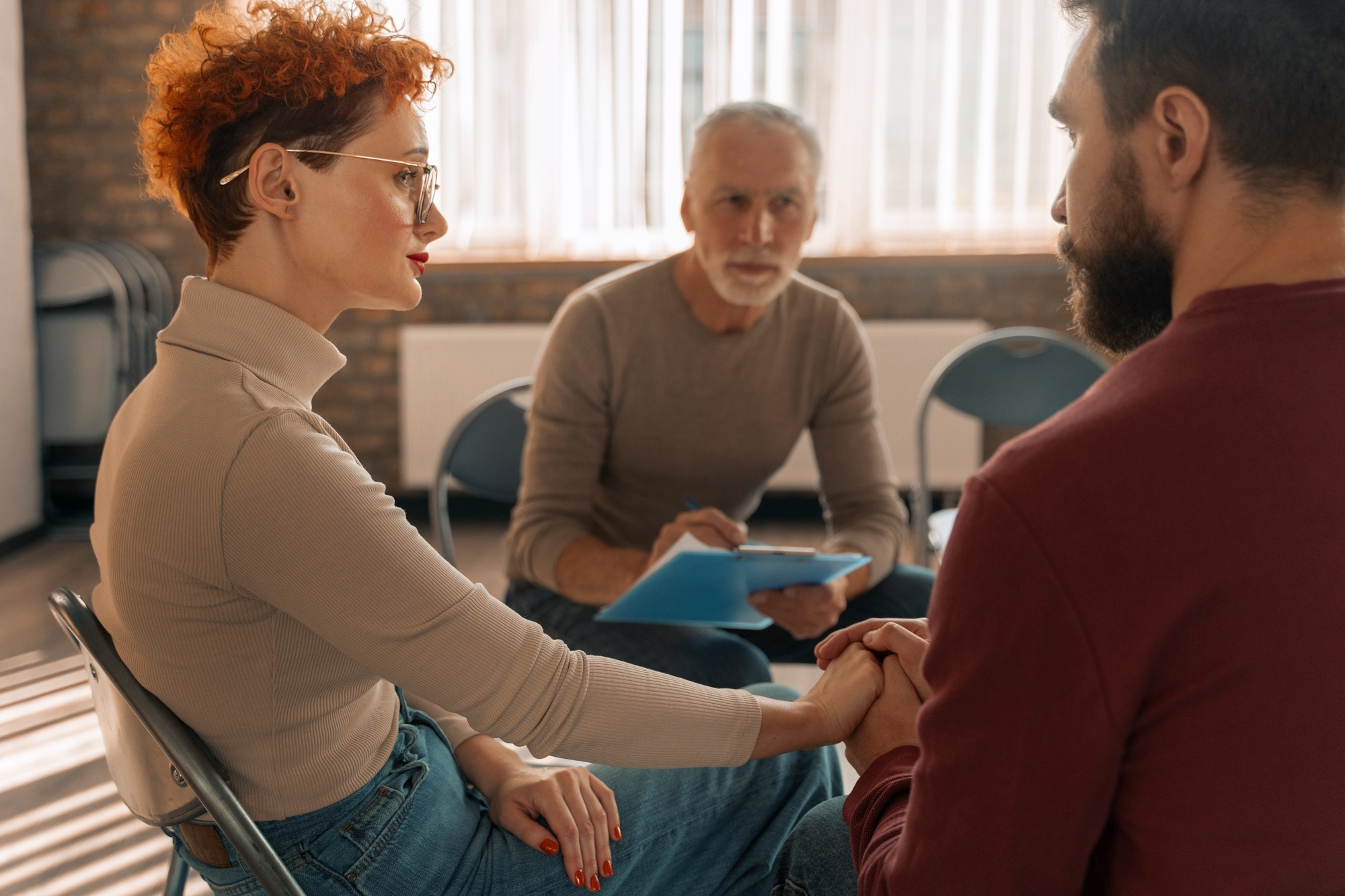 Woman and man holding hands while speaking with a therapist during individual counseling in Mount Pleasant, WI.