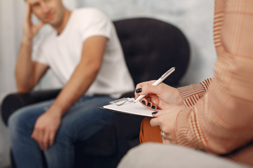 Man speaking with his therapist while she takes notes during addiction treatment at Axis Behavioral Health.