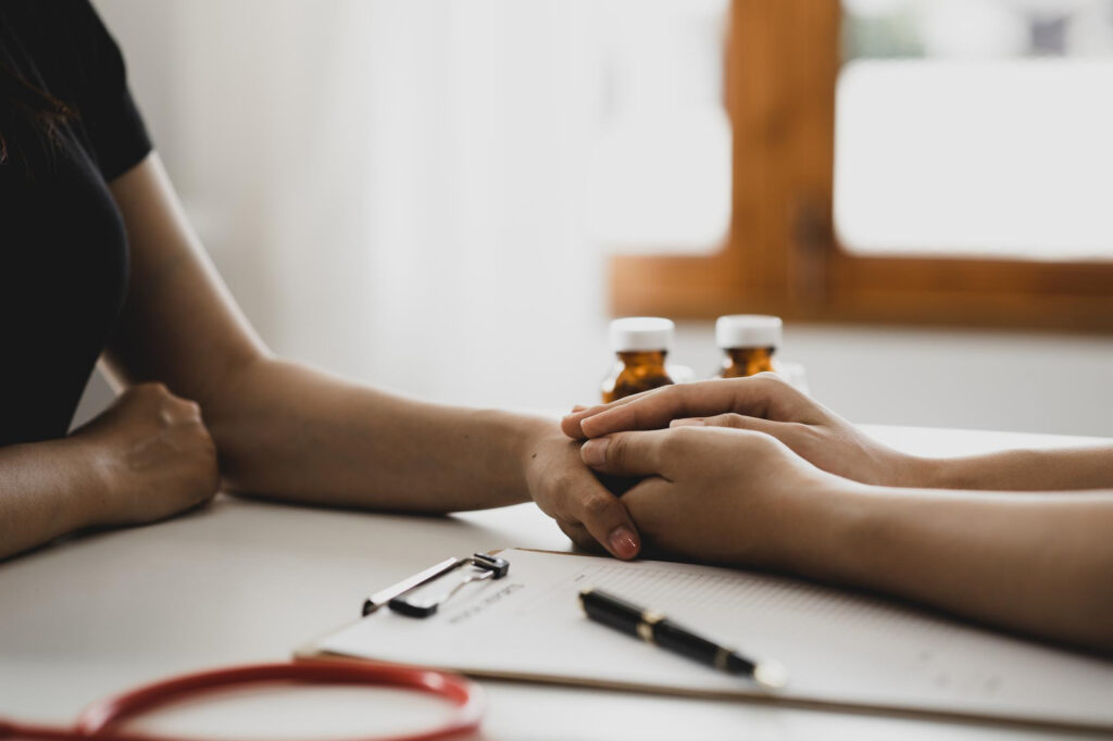 Doctor holding a patient’s hand while discussing medication management in Mount Pleasant, WI.