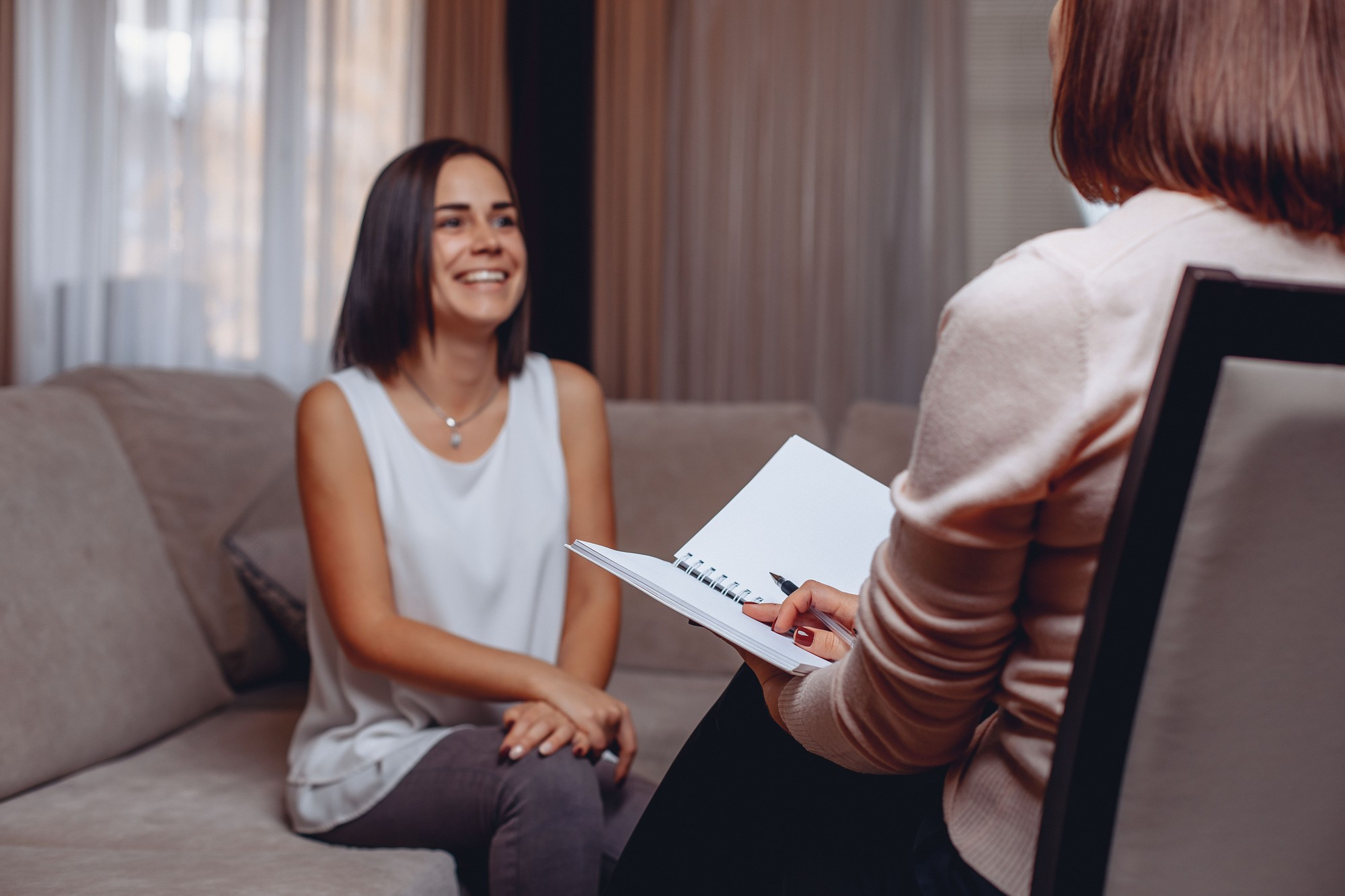 Woman smiling on a sofa while talking with her therapist during treatment in Mount Pleasant, WI.
