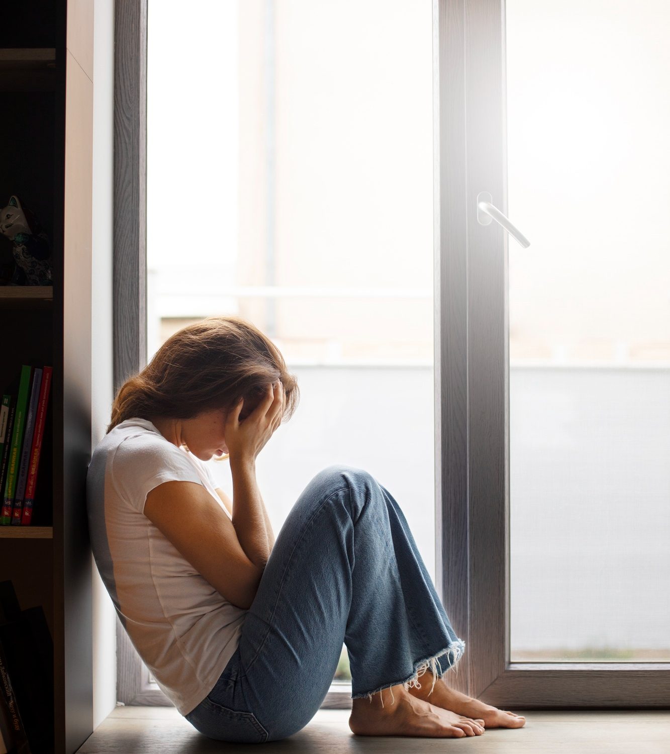 Woman sitting on the floor with her hands on her head during addiction treatment in Mount Pleasant, WI.