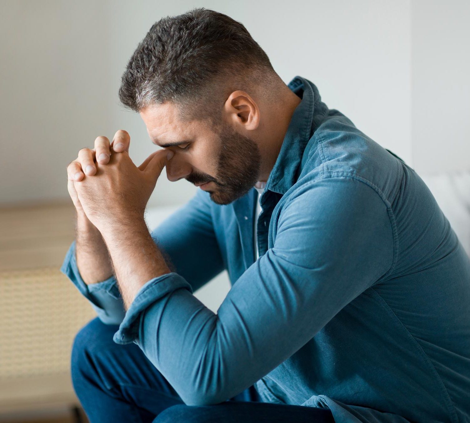 Thoughtful man sitting with his hands over his face during addiction treatment in Mount Pleasant, WI.